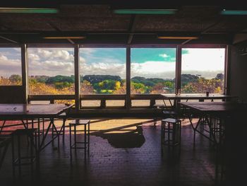 Empty chairs and tables by glass windows