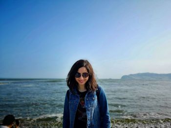Portrait of smiling young woman on beach against sky
