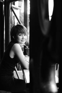 Side view of young woman looking through window at home