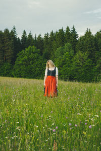 Rear view of woman standing on field against sky