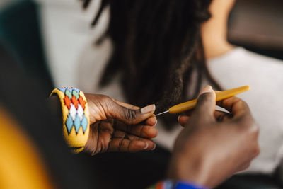 Cropped image of female barber making locs with crochet hook in salon