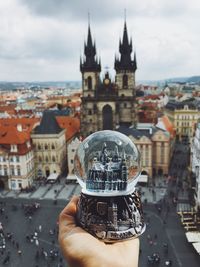Midsection of person holding cathedral against buildings in city