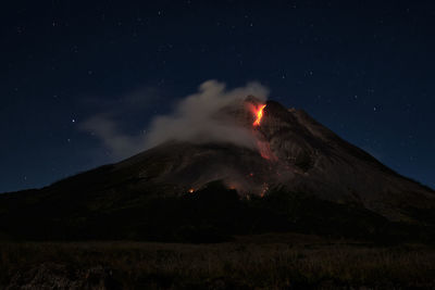 Smoke emitting from volcanic mountain against sky at night