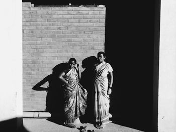 Friends standing against brick wall