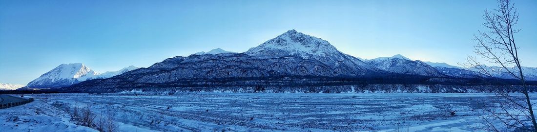 Scenic view of snow covered mountains against clear blue sky