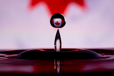Close-up of drop falling on red water