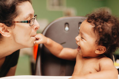 Laughing mother playing with son at home