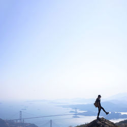 Man standing on mountain against clear sky during winter