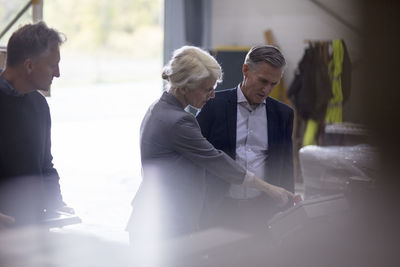 Business people operating machine while standing at industry