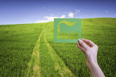 Hand holds green factory symbol