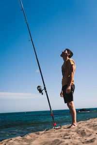 Full length of shirtless man on beach against sky