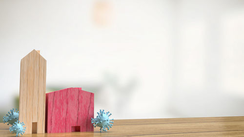 Close-up of red flower on table against wall