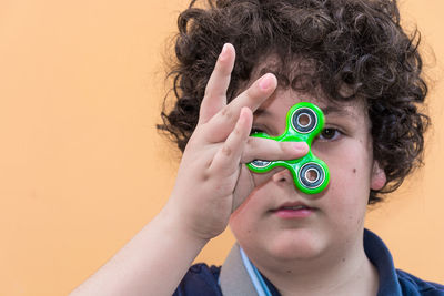 Portrait of boy playing with fidget spinner against wall