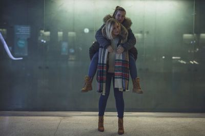 Young woman giving piggyback to friend 