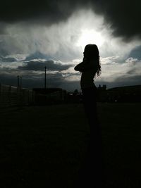 Man standing on field against cloudy sky