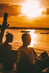 Rear view of silhouette people in sea during sunset