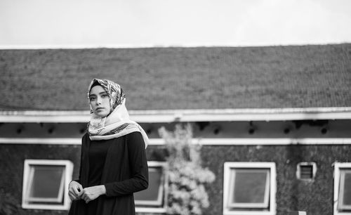 Young man in hijab standing against building