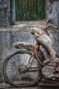 Abandoned bicycle against wall