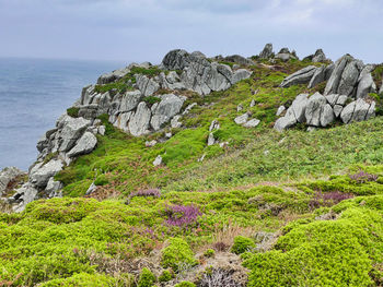 Scenic view of rocks by sea against sky