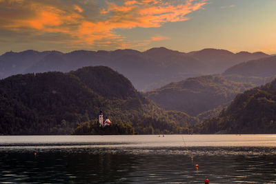 Scenic view of lake by mountains against sky during sunset