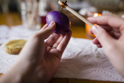 Cropped hands of girl making easter eggs at home