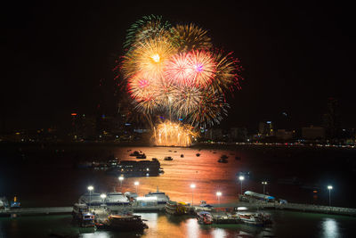 Firework display over sea against sky at night