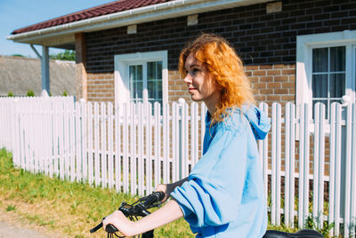 Portrait of young woman standing on footpath