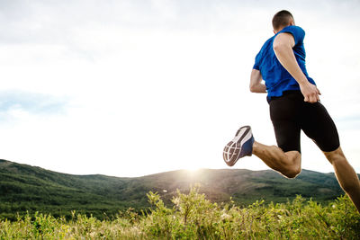 Full length of man running on field against sky