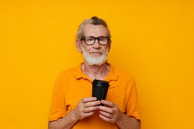 Portrait of young man using mobile phone against yellow background