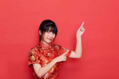 Young woman smiling against red background