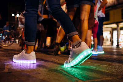 Low section of woman wearing illuminated shoes walking in city