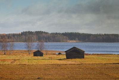 Two old barn houses stand on the autumn fields by a lake in the northern finland. 
