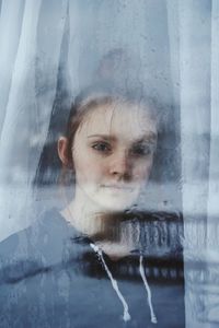 Close-up portrait of girl looking through glass window