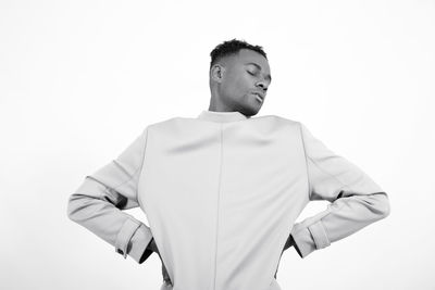 Portrait of young man holding hair over white background