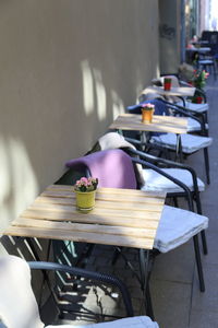 High angle view of outdoors cafe tables and chairs  lined up by a yellow wall 