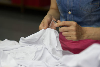 Midsection of woman stitching white textile