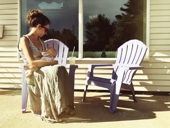 Woman with baby sitting on adirondack chair in back yard