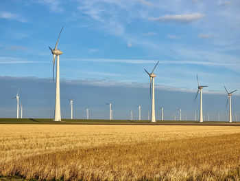 Windmills on field against sky