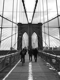 Rear view of man on suspension bridge against sky