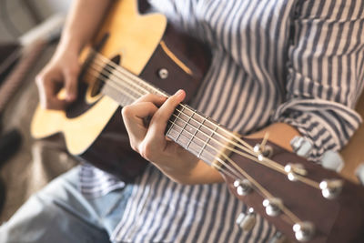 Midsection of man playing guitar