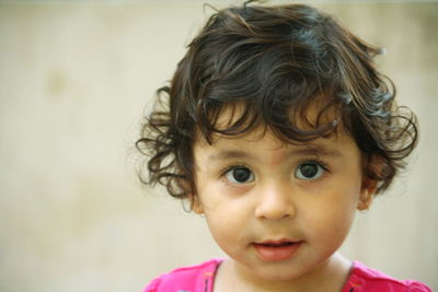 Close-up portrait of cute girl against wall