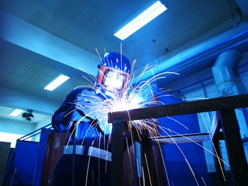 Welder welding metal in factory