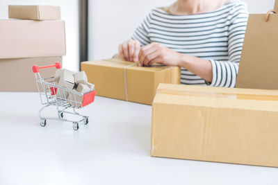 Midsection of woman tying gift box at table