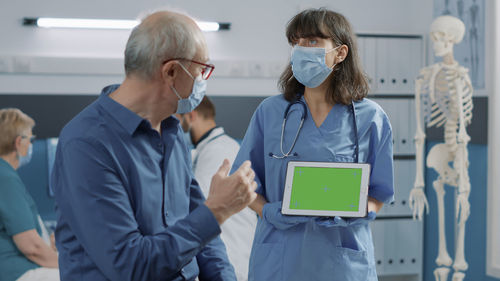 Nurse showing digital tablet to patient at clinic