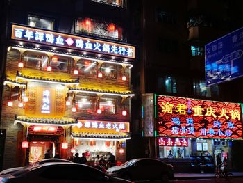 Illuminated street amidst buildings in city at night