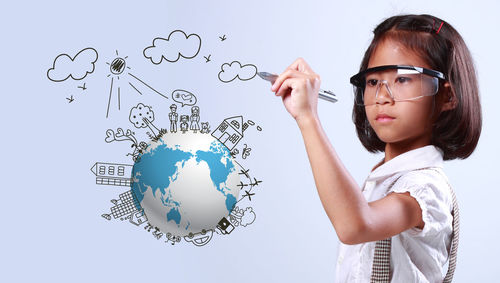 Digital composite image of girl drawing over earth against white background