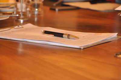 Close-up of paper with pen on wooden table