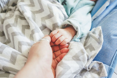 Cropped image of mother and baby holding hands