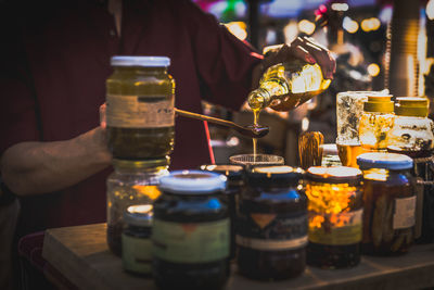 Man pouring honey from bottle into wooden spoon.