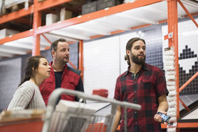 Salesman and couple looking away while standing in hardware store